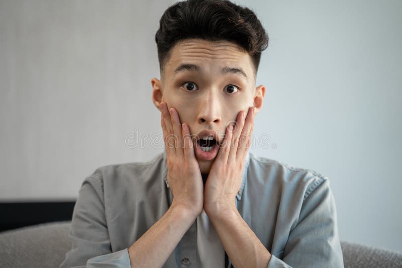 Young Asian Man Gets Scared Watching Horror TV Program Stock Image