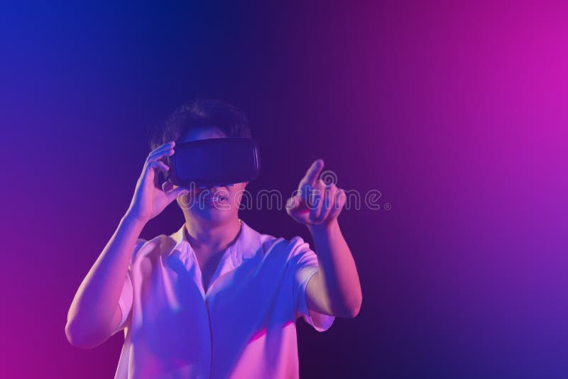 Young Asian man getting experience with VR virtual reality headset or 3D glasses on black background. Dark Tone. technology, gaming, entertainment concept