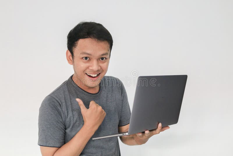 Young Asian man in grey t-shirt Feeling happy and smile with holding laptop in hand