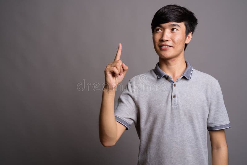 Young Asian Man Wearing Gray Polo Shirt Against Gray Background Stock ...