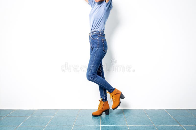 Young girl blue jeans brown shoes wall white.