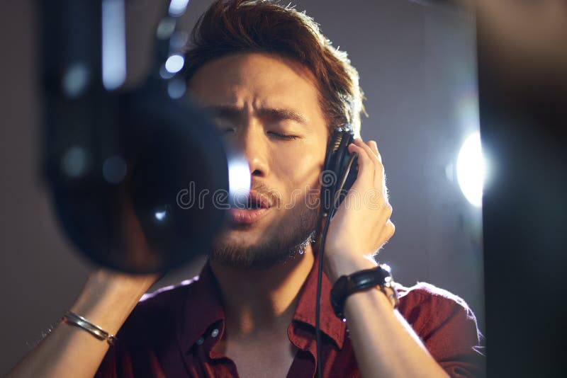 Young asian singer singing in recording studio
