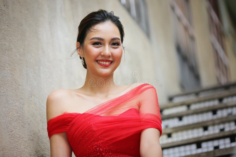 Young Asian Woman in a beautiful red dress looking at camera with smile. Fashion model, bride or pre-wedding concept.