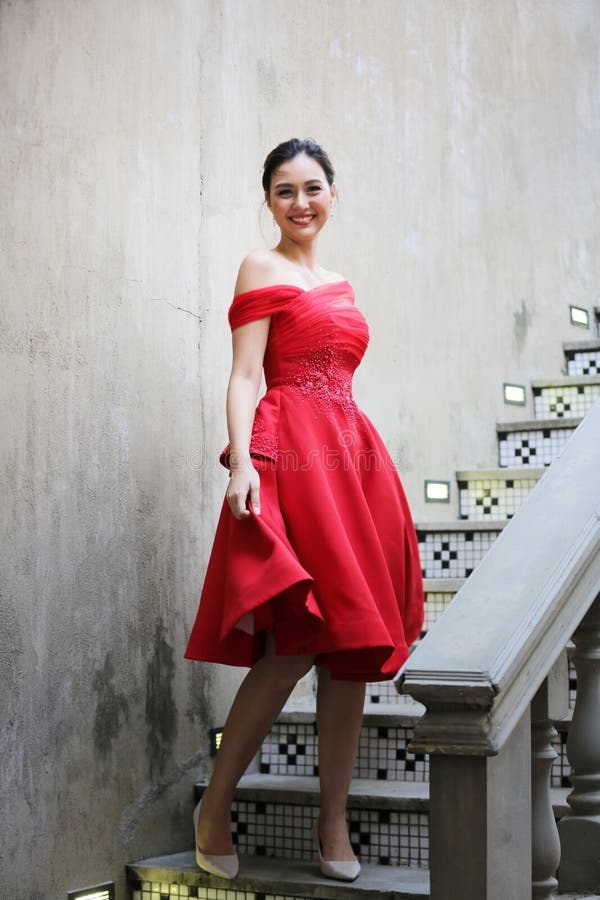 Young Asian Woman in a beautiful red dress looking at camera with smile. Fashion model, bride or pre-wedding concept.