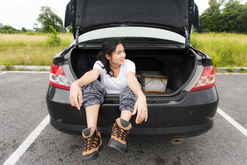 Young asian woman sitting in the car trunk