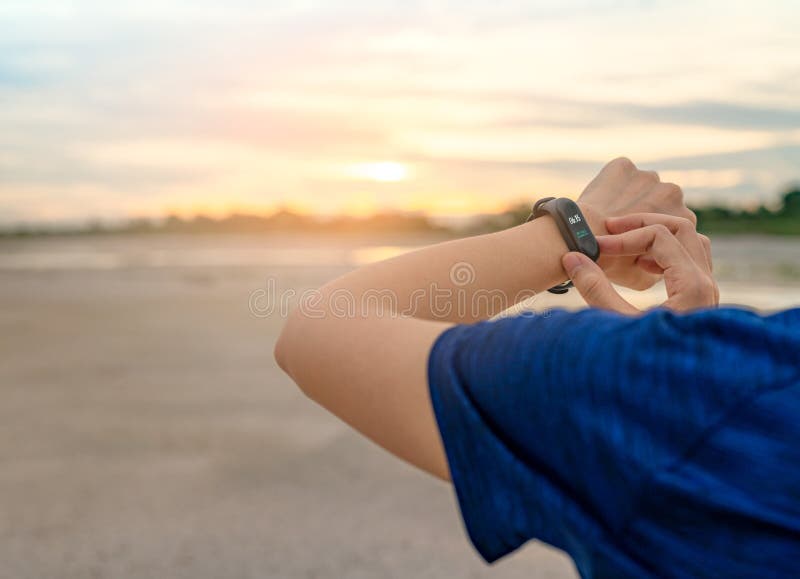 Young Asian woman touching smart band after running in the morning. Wearable computer. Heart rate monitor bracelet. Fitness device