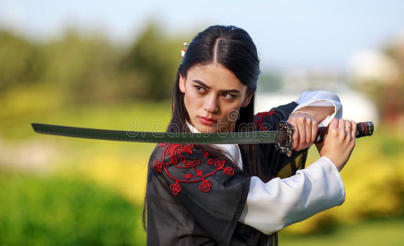 Young asian woman in traditional kimono trains in a fighting stance close-up portrait with katana sword samurai warrior girl in