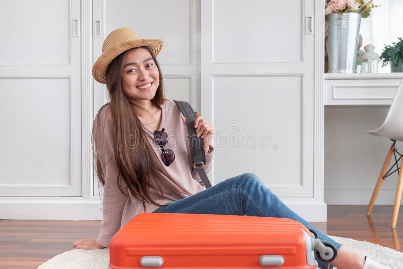 Young asian woman traveler prepare cloth and stuff into orange suitcase for holiday vacation at home.backpacker travel concept royalty free stock image Young asian woman traveler prepare cloth and stuff into orange suitcase for holiday vacation at home.backpacker travel concept royalty free stock image