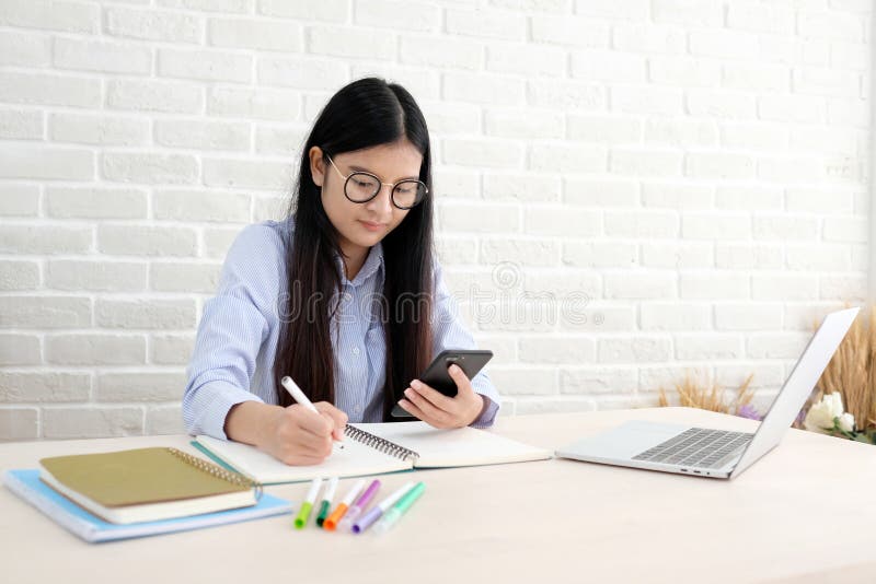 Young asian woman using smart phone while working at her office royalty free stock photos Young asian woman using smart phone while working at her office royalty free stock photos