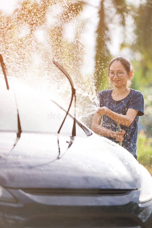 Young asian woman water spray her car with water tube washing it royalty free stock image Young asian woman water spray her car with water tube washing it royalty free stock image