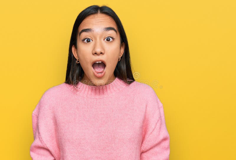 Young asian woman wearing casual winter sweater afraid and shocked with surprise and amazed expression, fear and excited face royalty free stock photos