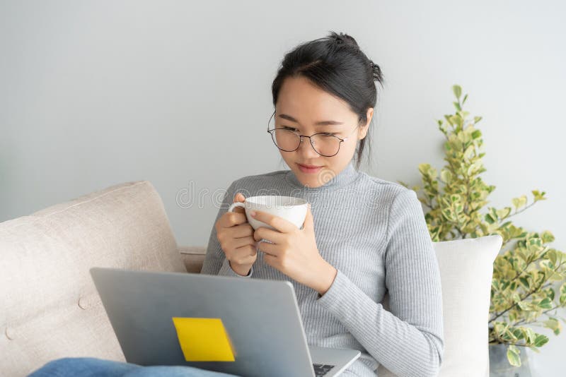 Young asian woman working on laptop in the home office desk. And enjoying cup of coffee royalty free stock photos Young asian woman working on laptop in the home office desk. And enjoying cup of coffee royalty free stock photos