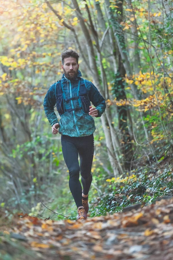 Young athlete with beard runs in the rain on a trail with technical clothing royalty free stock photos Young athlete with beard runs in the rain on a trail with technical clothing royalty free stock photos