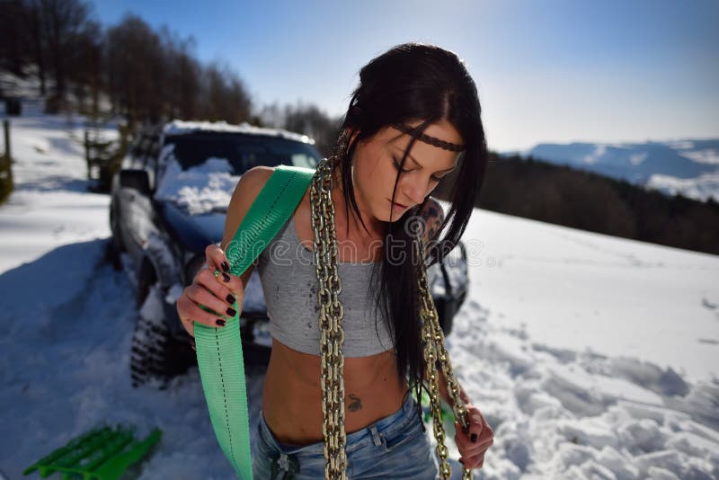 Young athletic woman pulling car in winter