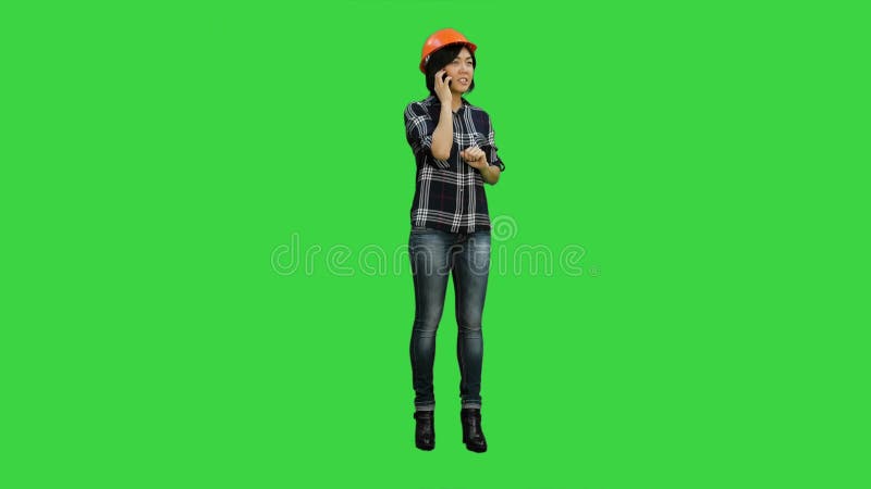 Young attractive asian engineer woman standing having a phone call on a Green Screen, Chroma Key