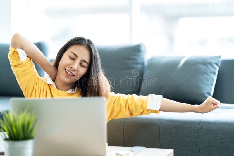Young attractive asian woman work at home wearing casual yellow shirt in living room