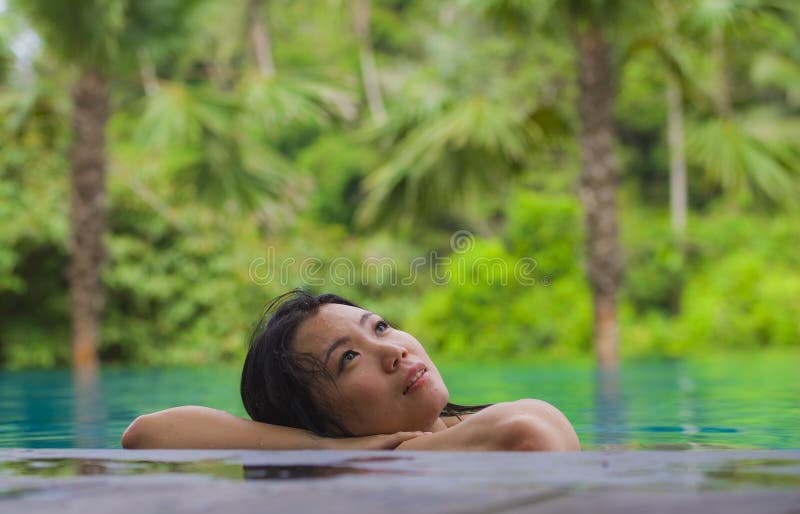Young attractive and beautiful Asian Chinese woman relaxing happy at tropical beach resort swimming at jungle infinity pool royalty free stock images Young attractive and beautiful Asian Chinese woman relaxing happy at tropical beach resort swimming at jungle infinity pool royalty free stock images