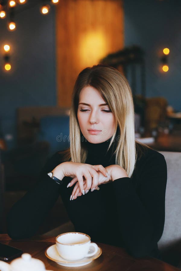 Young attractive blonde woman drinks tea in restaurant stock photo Young attractive blonde woman drinks tea in restaurant stock photo