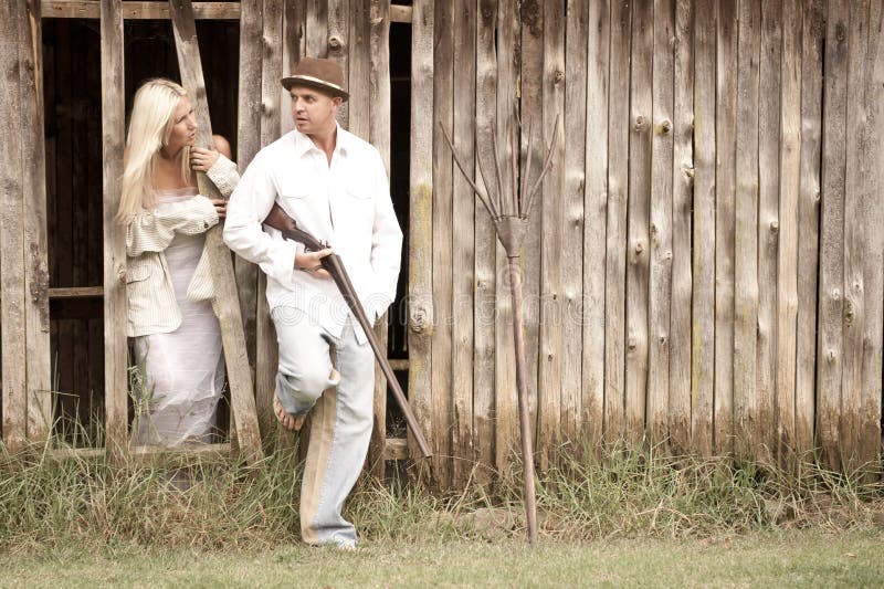 Young attractive couple standing together against wooden barn wall