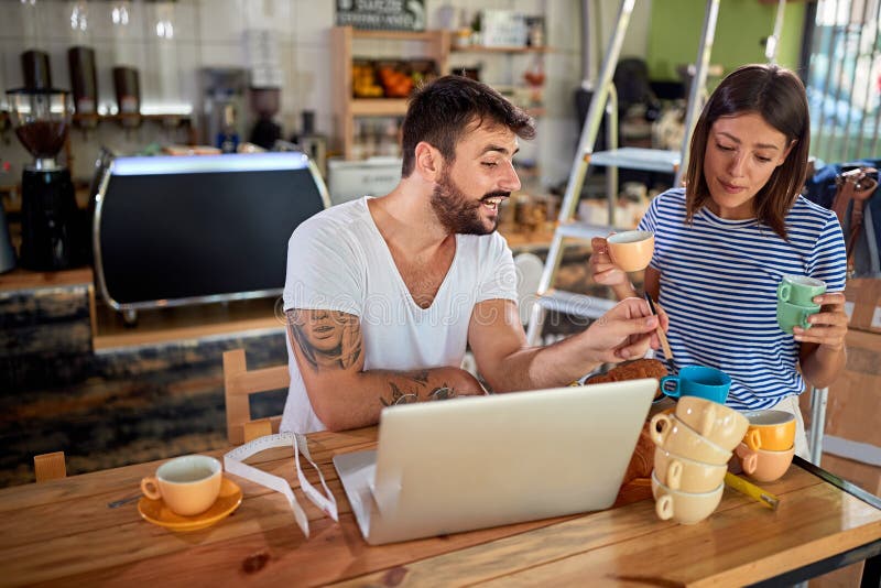 Young attractive couple talking, discussing, choosing  coffee cups for cafeteria that they are about to open. starting business