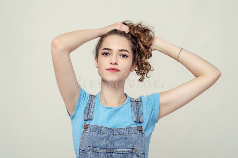 Young attractive girl raised hair with hands up. Nice smile. Den