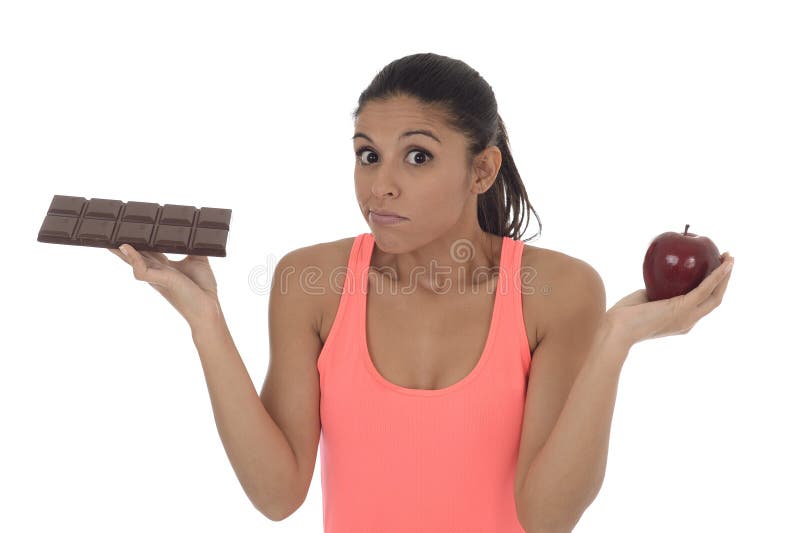 Young attractive hispanic woman in fitness top holding apple fruit and chocolate bar in her hands stock image Young attractive hispanic woman in fitness top holding apple fruit and chocolate bar in her hands stock image