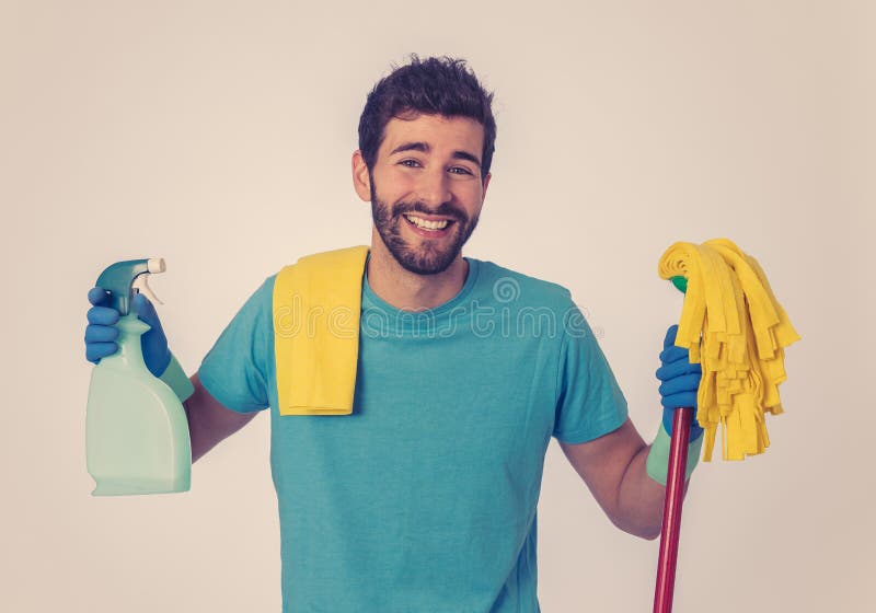 Young attractive man holding cleaning tools and products in bucket isolated in blue background. Breaking gender stereotypes. Portrait of attractive happy man royalty free stock images Young attractive man holding cleaning tools and products in bucket isolated in blue background. Breaking gender stereotypes. Portrait of attractive happy man royalty free stock images