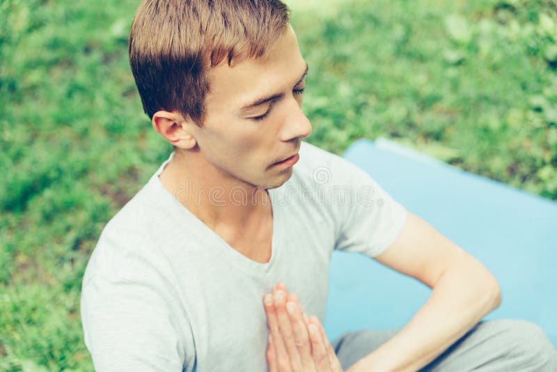 A young attractive man practices yoga in nature and meditates with his eyes closed in the lotus position stock photos A young attractive man practices yoga in nature and meditates with his eyes closed in the lotus position stock photos