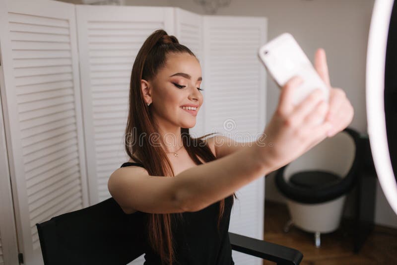 Young attractive model make a selfie after makeup in beauty studio. She use a ring lapm for photo. Background of white stock images Young attractive model make a selfie after makeup in beauty studio. She use a ring lapm for photo. Background of white stock images