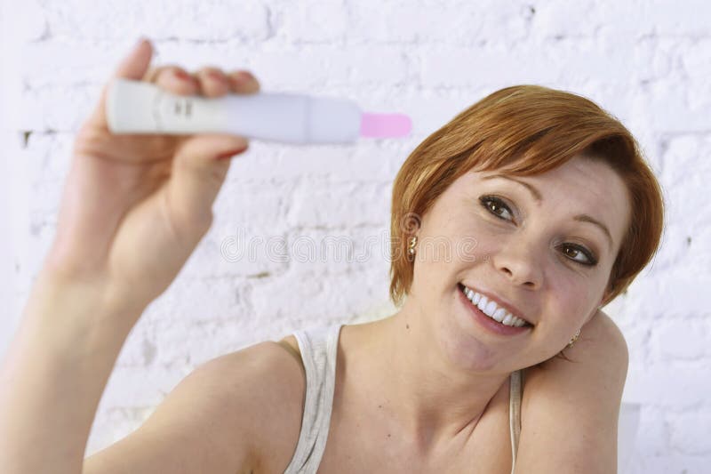 Young attractive pregnant woman holding happy positive result pregnancy test sitting on bed stock images Young attractive pregnant woman holding happy positive result pregnancy test sitting on bed stock images