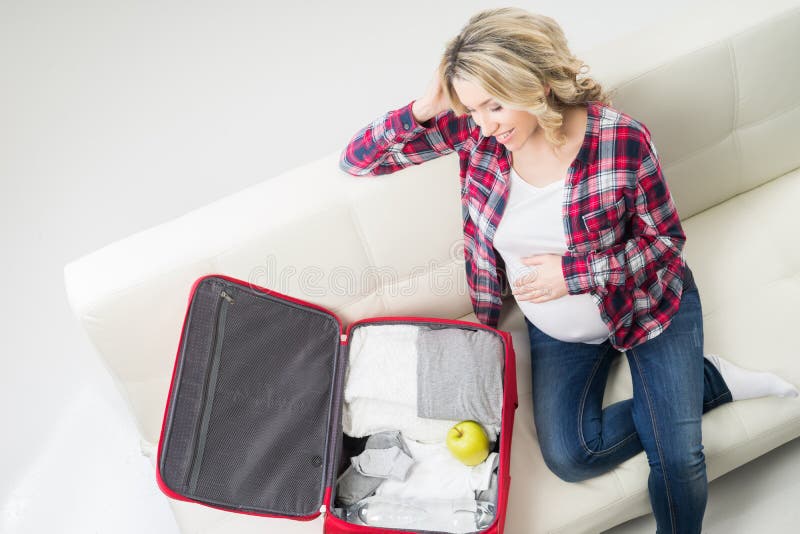 Young attractive pregnant woman packing children's wear stock photo Young attractive pregnant woman packing children's wear stock photo