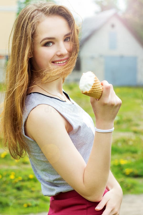 Young attractive smiling girl in a sunny day with an ice cream in the hands...