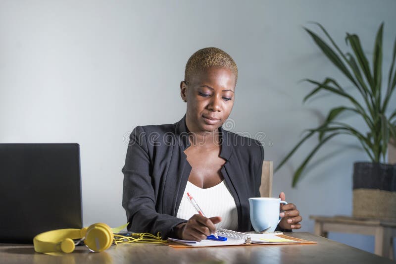 Young attractive and successful black afro american woman in business jacket working serious at office laptop taking notes writing in notepad looking confident in work success concept. Notes office stock images, royalty-free photos and pictures
