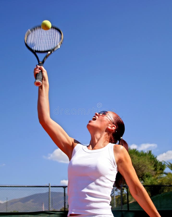 Young attractive tanned healthy woman playing tennis in midday sun with blue sky royalty free stock photography Young attractive tanned healthy woman playing tennis in midday sun with blue sky royalty free stock photography