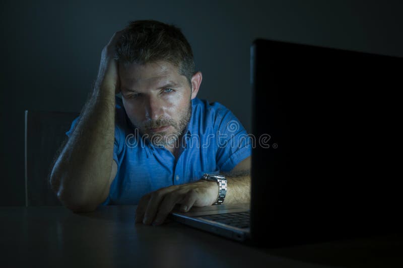 Young attractive and tired unshaven man working late night on laptop computer in the dark feeling frustrated and exhausted in royalty free stock image Young attractive and tired unshaven man working late night on laptop computer in the dark feeling frustrated and exhausted in royalty free stock image