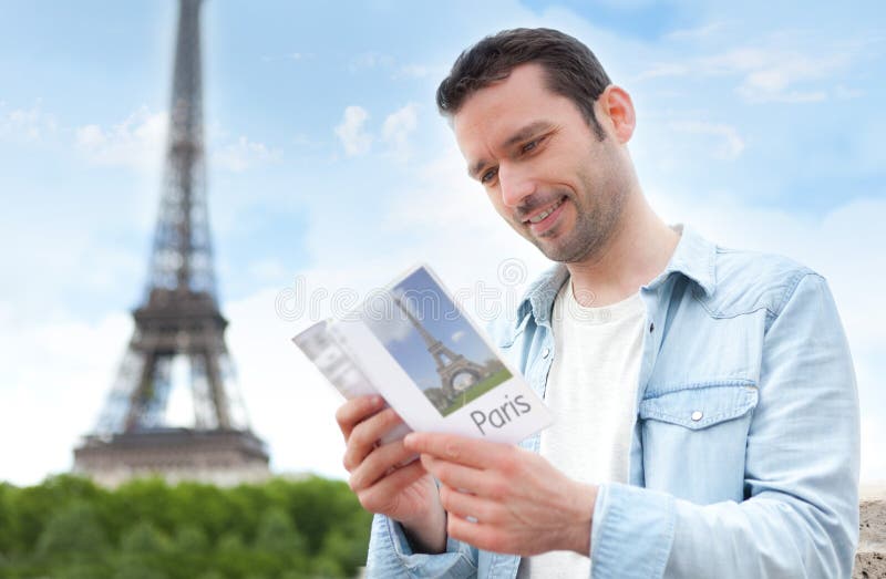 Young attractive tourist reading a guide of Paris