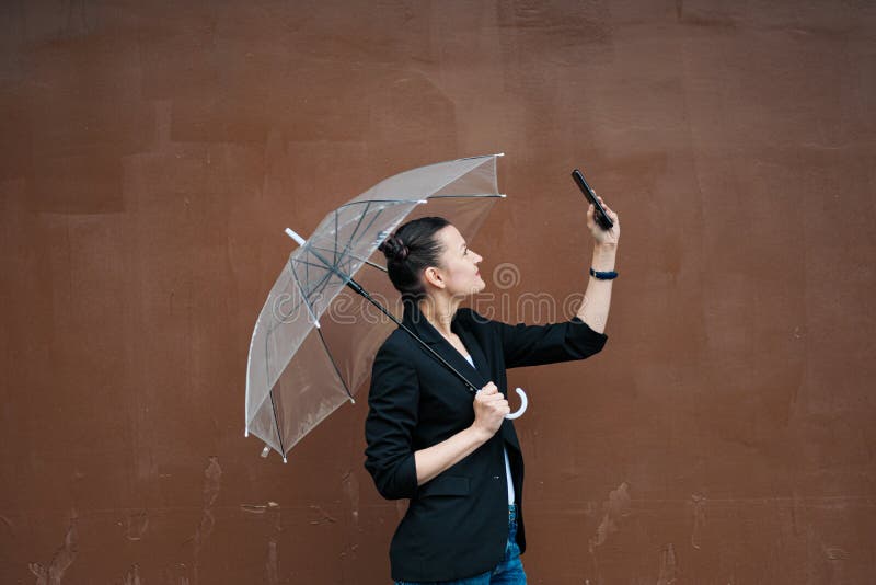 Young attractive woman in black jacket and blue jeans posing outdoor against background of building. royalty free stock photos Young attractive woman in black jacket and blue jeans posing outdoor against background of building. royalty free stock photos