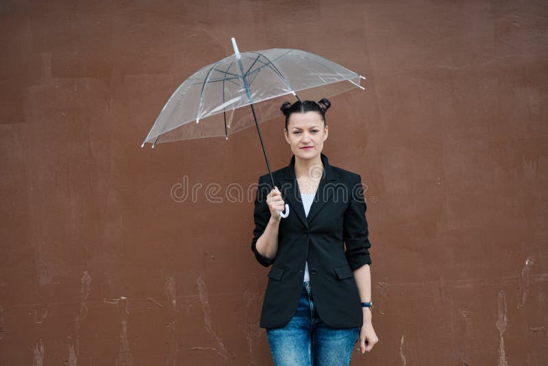 Young attractive woman in black jacket and blue jeans posing outdoor against background of building. royalty free stock images Young attractive woman in black jacket and blue jeans posing outdoor against background of building. royalty free stock images