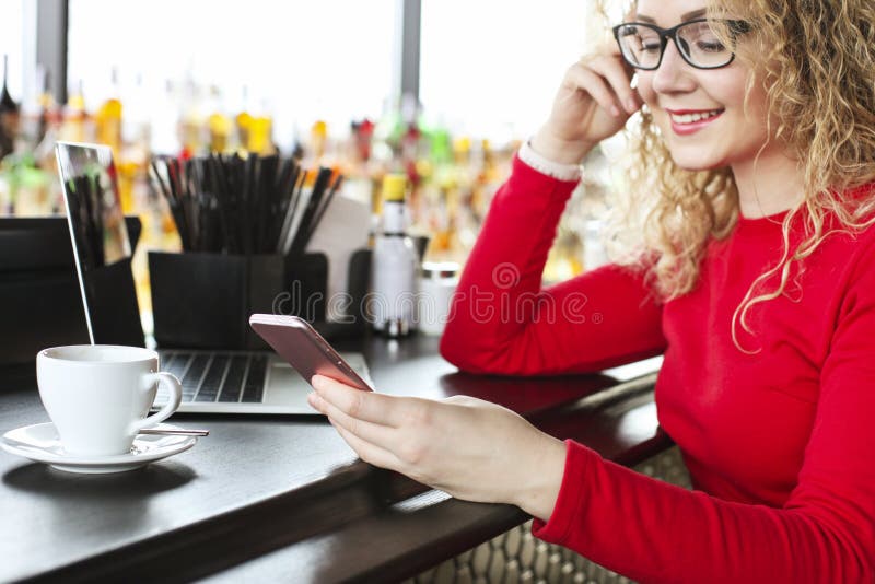Young attractive woman checking her trendy smartphone for new messages. Female freelancer working at hipster coffe place with big royalty free stock photo Young attractive woman checking her trendy smartphone for new messages. Female freelancer working at hipster coffe place with big royalty free stock photo