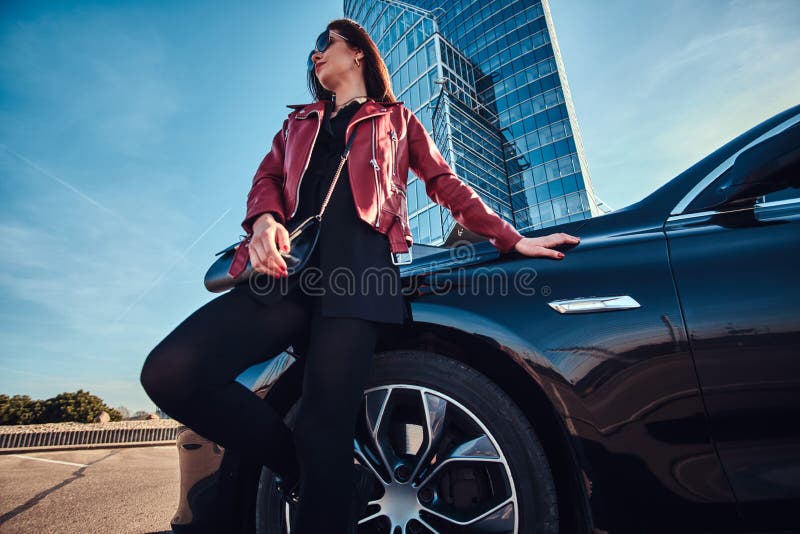 Young attractive woman is chilling in bright sunny day next to her car stock image Young attractive woman is chilling in bright sunny day next to her car stock image