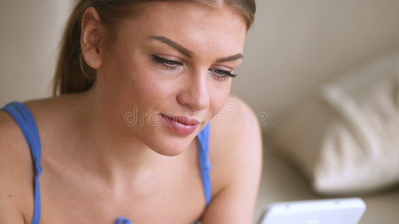 Young attractive woman holding smartphone, looking at camera and smiling