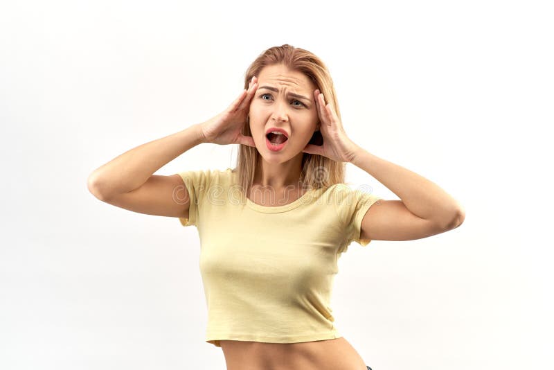 Young attractive woman posing in Studio isolated portrait, hands on head and mouth wide open. Shocked, stress, horror emotions on her face and a headache