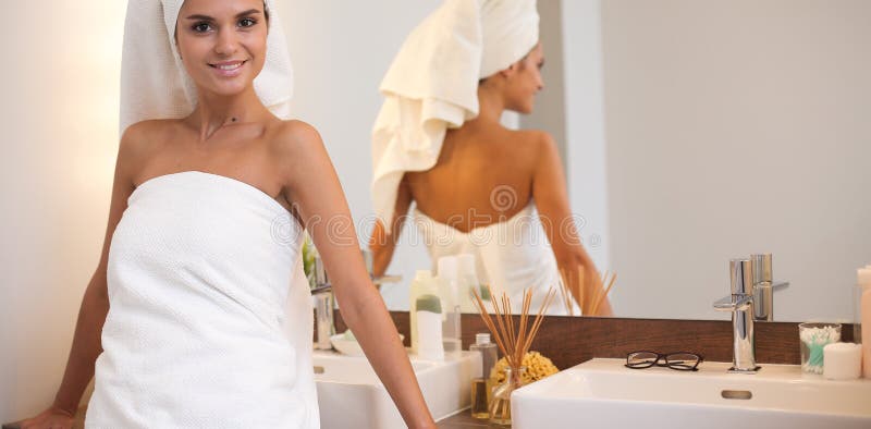 Young attractive woman standing in front of bathroom mirror