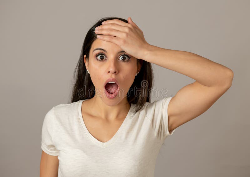 Close up portrait of a beautiful young latin hispanic woman with a surprised and shocked face looking amazed with wide eyes and mouth open.Human facial expressions and emotions. Gray background. Close up portrait of a beautiful young latin hispanic woman with a surprised and shocked face looking amazed with wide eyes and mouth open.Human facial expressions and emotions. Gray background