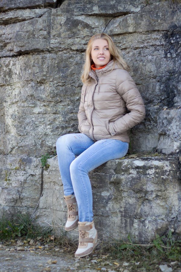 Young Attractive Woman in Warm Clothes Sitting Against Rocky Wall Stock ...