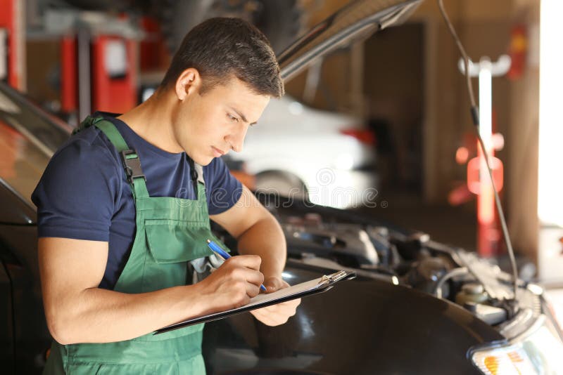 Young Auto Mechanic With Clipboard Near Car In Service Center Stock