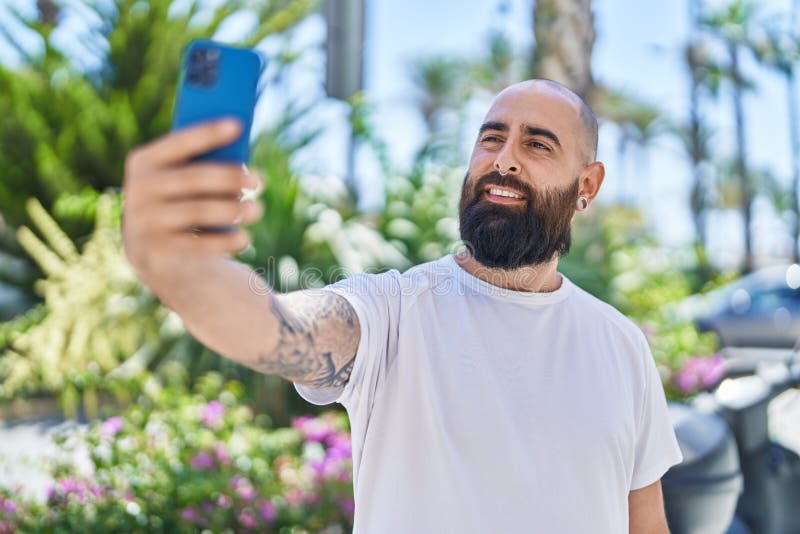 Young bald man smiling confident making selfie by the smartphone at park royalty free stock photos