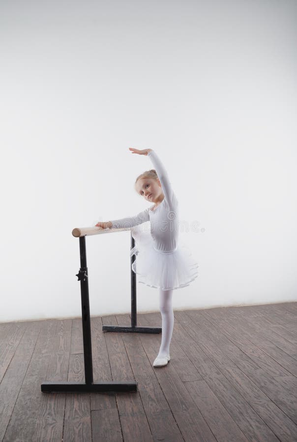 Young ballerina girl in a white tutu. Adorable child dancing classical ballet in a white studio with wooden floor. Children dance. stock photos Young ballerina girl in a white tutu. Adorable child dancing classical ballet in a white studio with wooden floor. Children dance. stock photos
