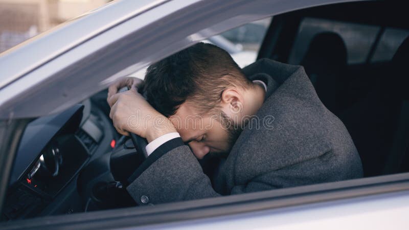 Young bearded business man sitting in car very upset and stressed after hard failure and moving in traffic jam royalty free stock photography Young bearded business man sitting in car very upset and stressed after hard failure and moving in traffic jam royalty free stock photography