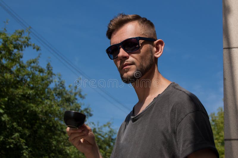 Young bearded man with a cup of coffee in his hand against the blue sky on a sunny summer day royalty free stock images Young bearded man with a cup of coffee in his hand against the blue sky on a sunny summer day royalty free stock images